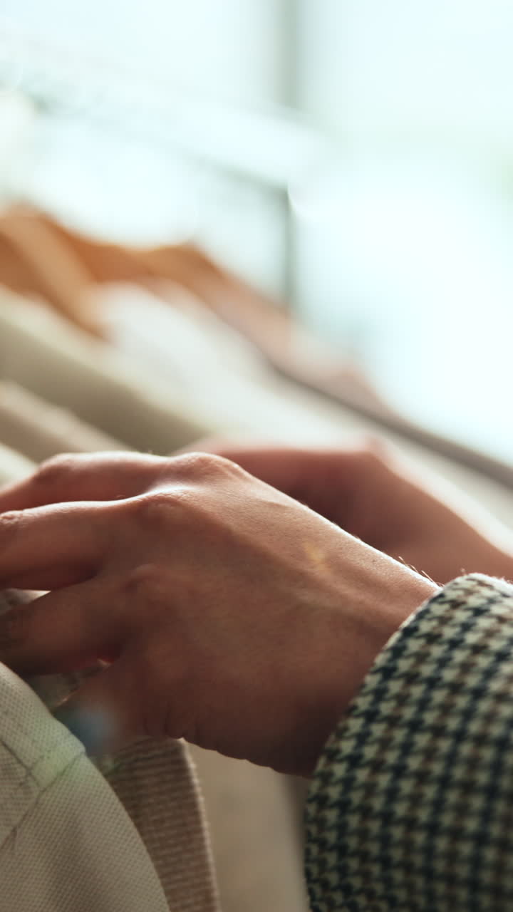 Close Up of Hands Browsing Clothes on a Rack