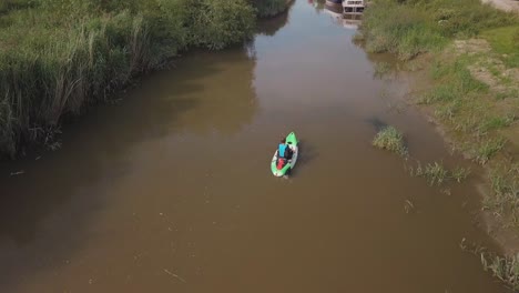 man kayaking on meandering river, drone follows and pans up to reveal beautiful landscape in the background