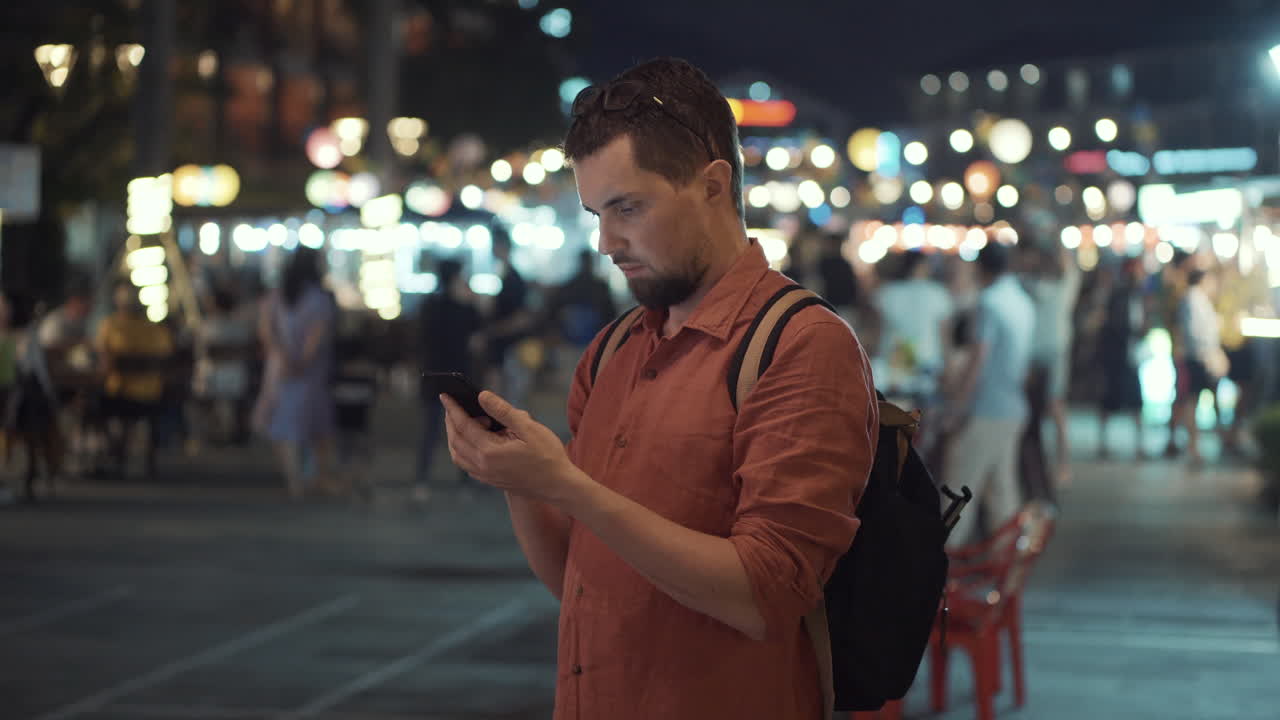 hombre usando el teléfono en un mercado nocturno