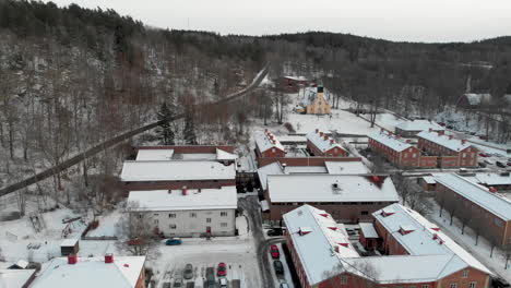 panning aerial shot of snow covering ground and buildings in tiny swedish town