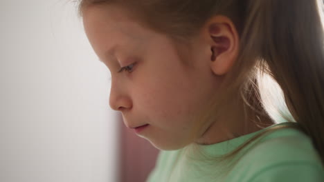 Little-girl-looking-downward-profile-portrait-in-light-room