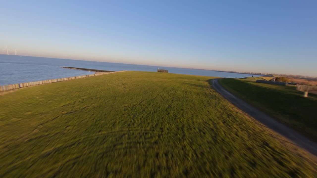 Fast shot above a bicycle path on a dyke next to the sea. High angle