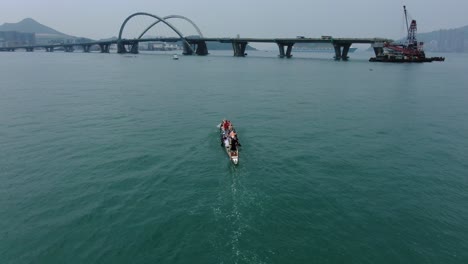 Dragon-Boat-team-rowing-to-the-pace-of-an-onboard-Drummer,-Aerial-view