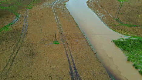 aerial shot of canal between wet agriculture fields during monsoon season