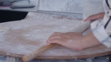 hands rolling dough on a wooden board