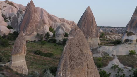 rotación alrededor del primer plano de la formación de roca natural de la chimenea de hadas sobre campos de hierba en capadocia, turquía