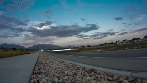 traffic speeds along the highway as an evening cloudscape passes over the mountains - static time lapse