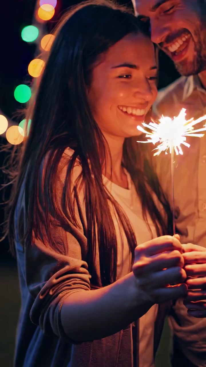 Coppia gioiosa che tiene stelle filanti e festeggia di notte