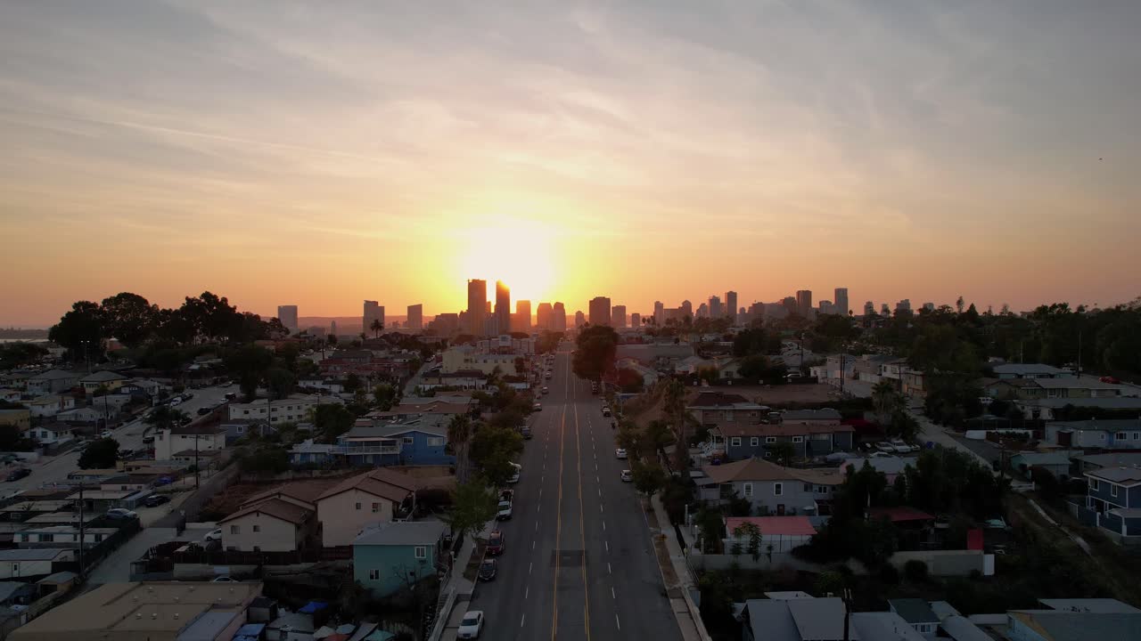 Drone aereo che sale sopra gli edifici per rivelare uno skyline vibrante al tramonto con orizzonte luminoso e dettagli urbani