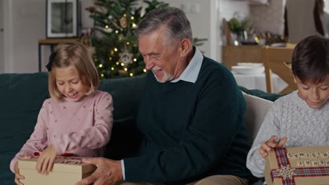 el abuelo mayor comparte los regalos de navidad con los niños.