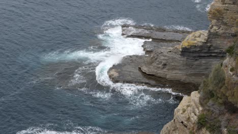 slow motion of ocean waves crashing over rock face, tasmania, australia