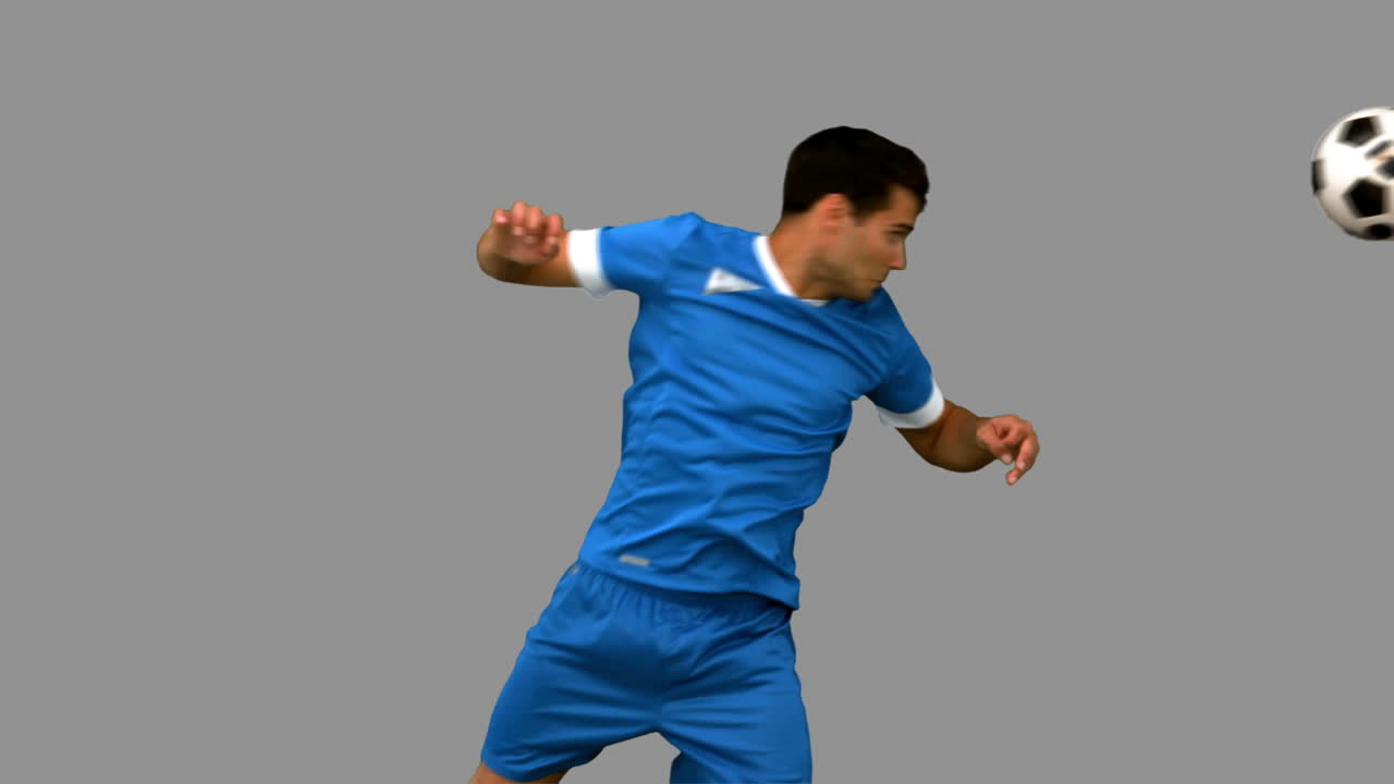 회색 스크린에서 축구를 치는 잘생긴 남자