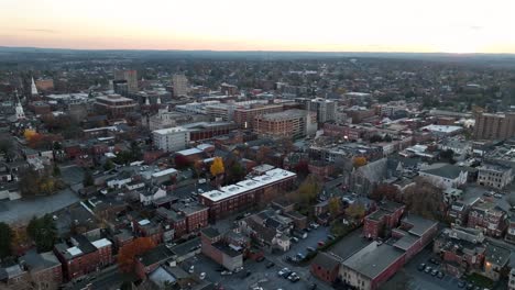 aerial establishing shot of historic town of united states in fall. colored trees during autumn season. row of ancient houses and apartments. parking cars after sunset time. wide shot.