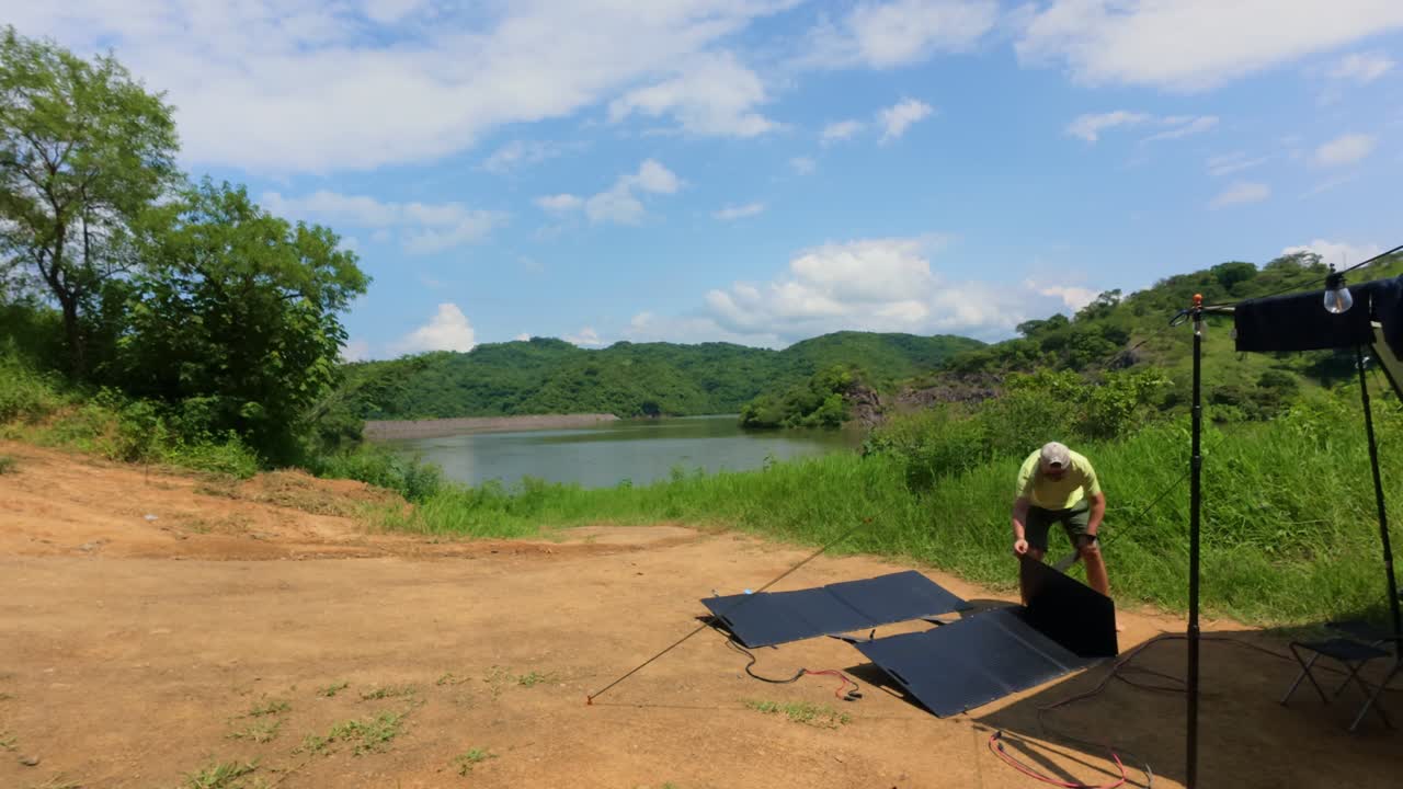 Man installs folding solar panels at campsite near lake in Presa El Carrizo, Jalisco, Mexico