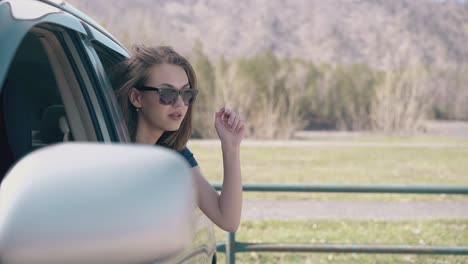 Mujer-Rubia-Con-Camiseta-Negra-Mira-Desde-El-Coche-A-Las-Tierras-De-Cultivo