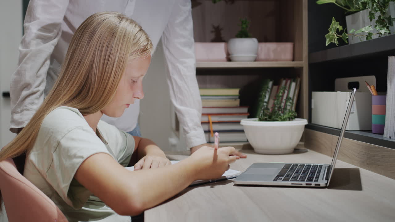The older brother helps his sister with homework, their cat is sitting next to him. Study at home
