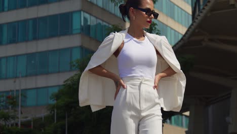 a young woman in a business suit walking in the city with tall buildings in the background