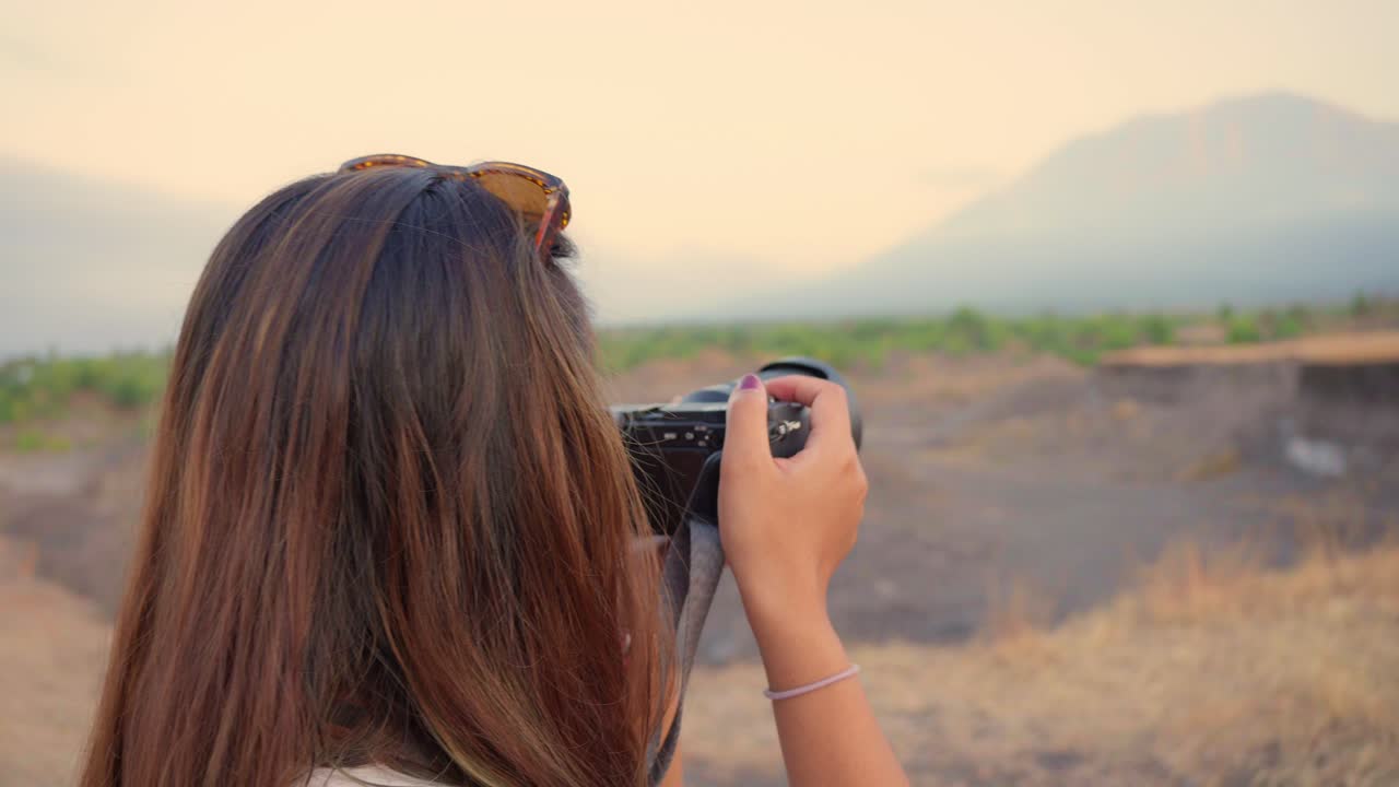 imágenes en cámara lenta de una mujer capturando fotos panorámicas con una cámara en la sabana de kubu, bali