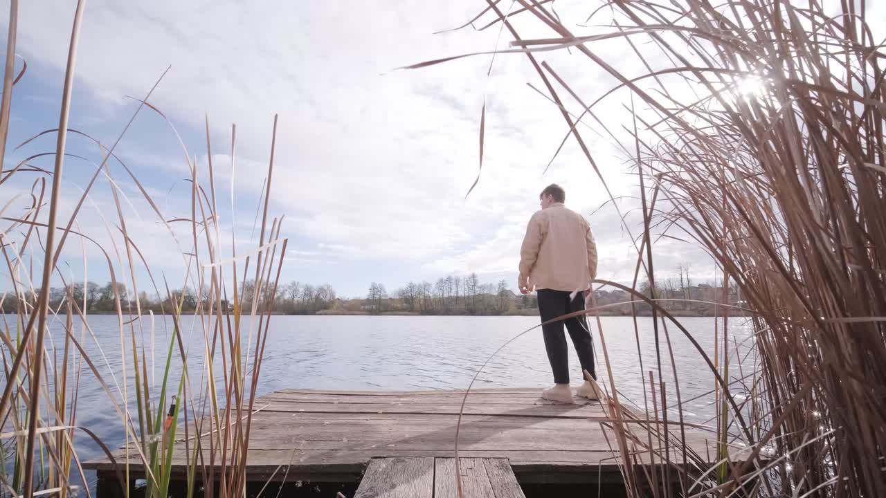 Man walks on wooden pier in a autumn day