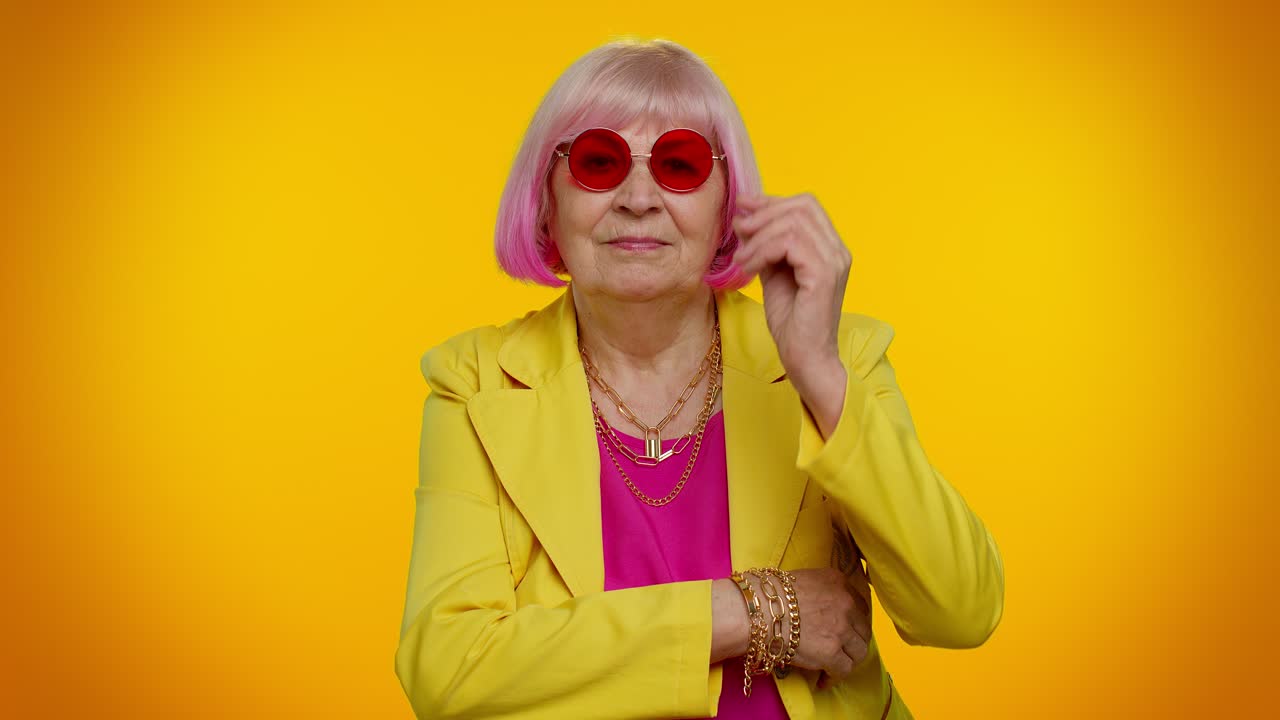 feliz lúdica elegante anciana abuela mujer con gafas de sol parpadeando el ojo, mirando a la cámara con una sonrisa