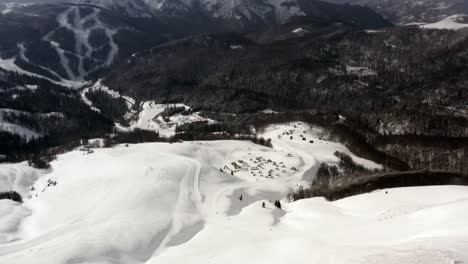 AERIAL---Snowy-winter-in-mountains-at-Kolasin-ski-resort,-Montenegro,-pan-right