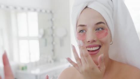 una mujer caucásica feliz de talla plus con bata de baño poniendo crema en la cara en cámara lenta.