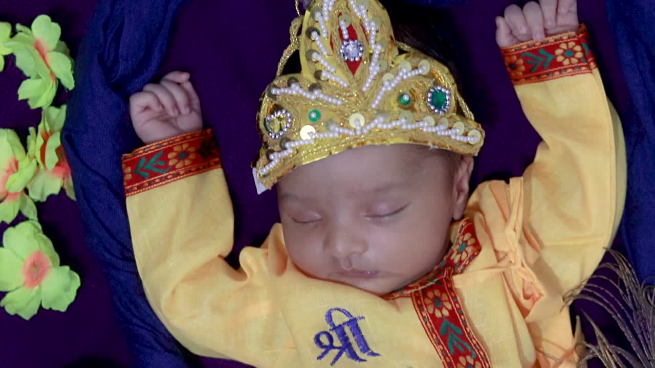 bebé recién nacido en krishna vestido con accesorios en columpio desde un ángulo único en expresión diferente