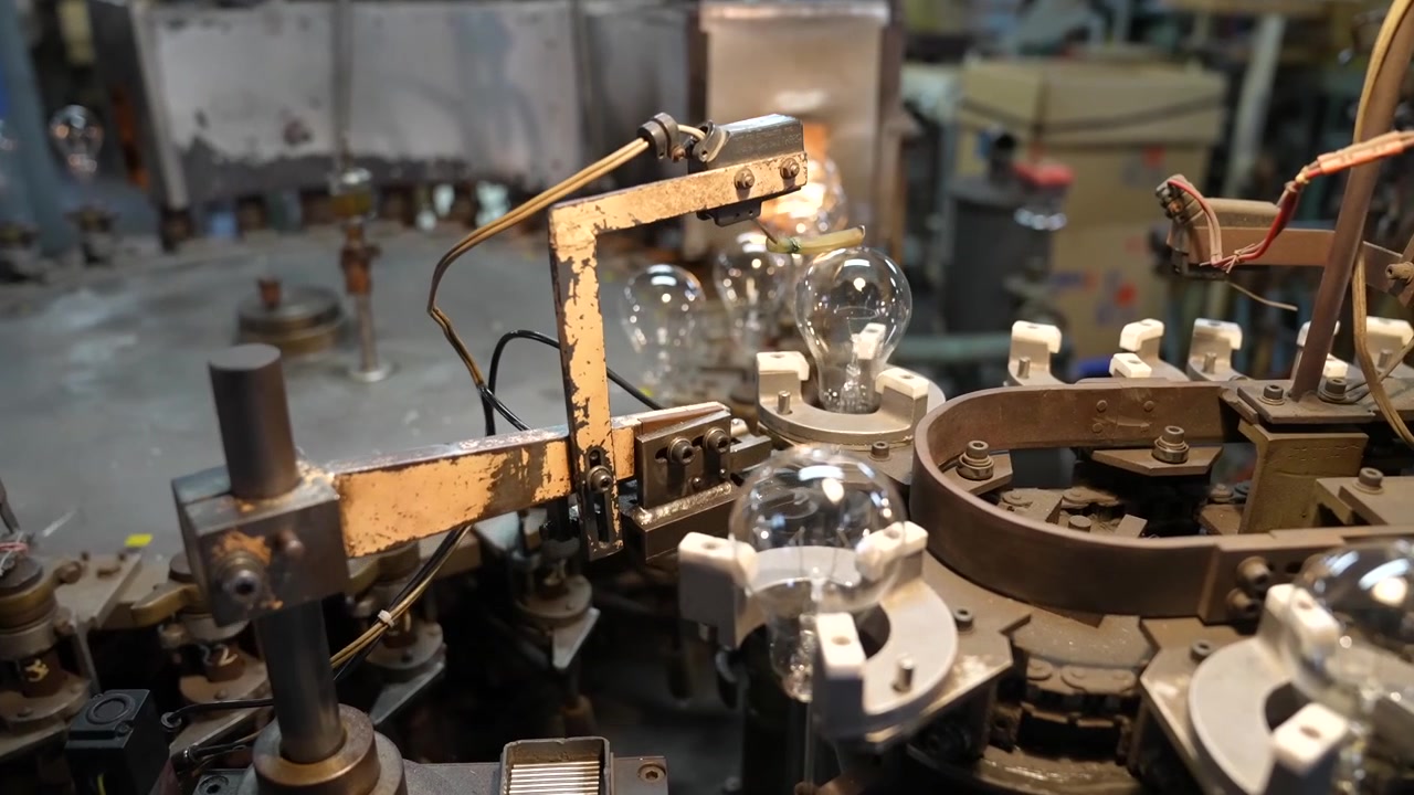 Mechanical arm sealing a glass bulb envelope onto its base fixture
