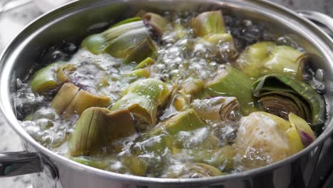 Boiling and cooking artichokes in saucepan, closeup