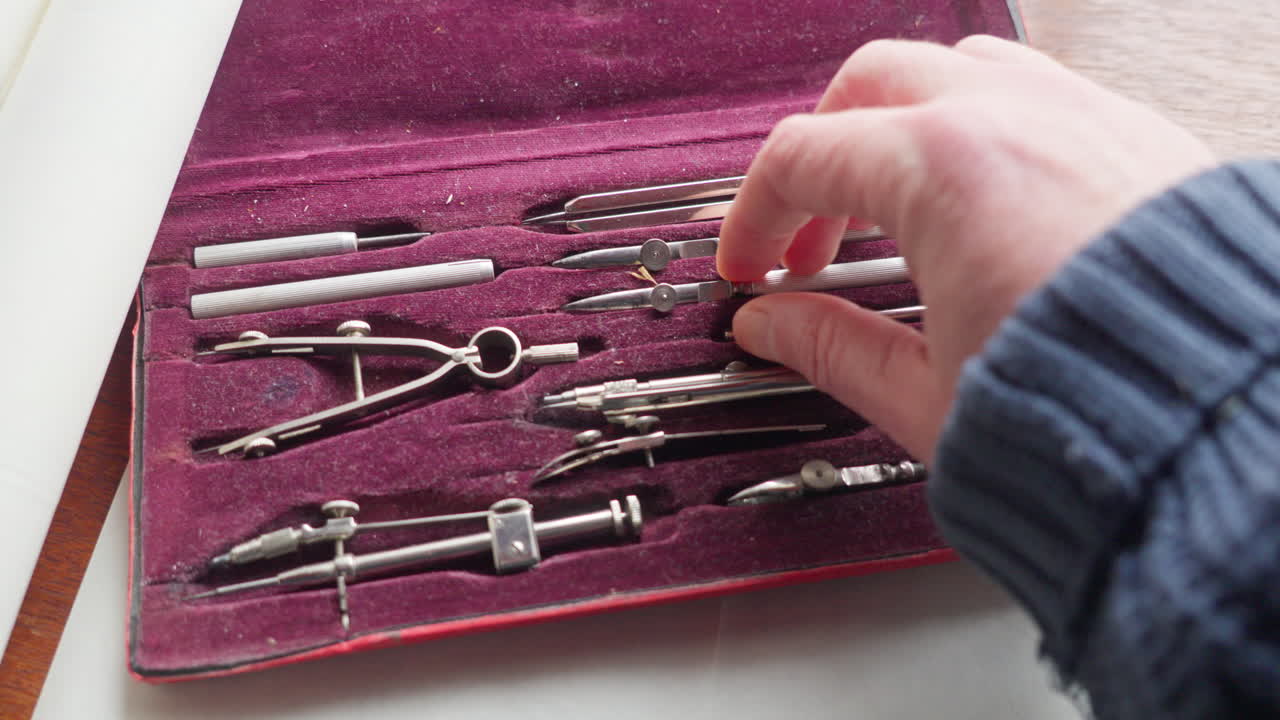 POV shot of a hand choosing a tool from a drafting set, capturing decision-making and preparation in a precise design process