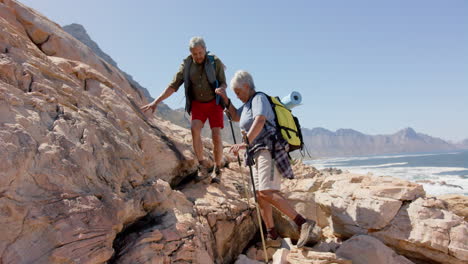 Happy-senior-biracial-couple-in-mountains-hiking,-in-slow-motion