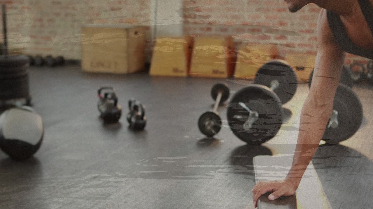 Male gym-goer bracing on bench in gym, grabbing dumbbell and performing single-arm row for fitness