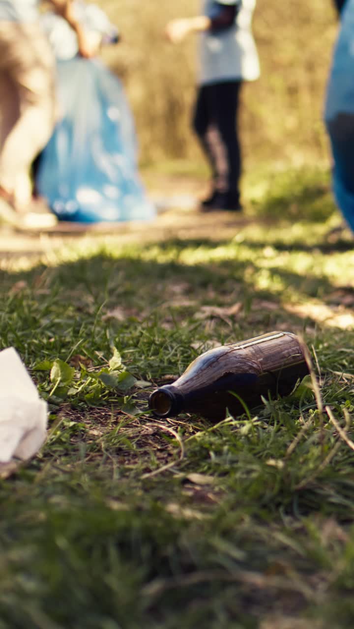 Close-up of Hands Picking Up Litter from Grassy Ground