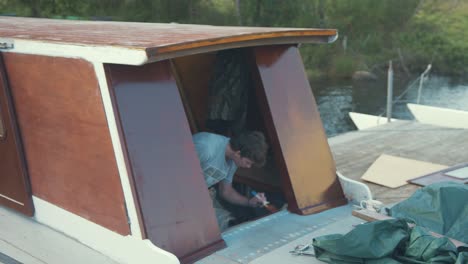 young man painting wooden boat wheelhouse cabin