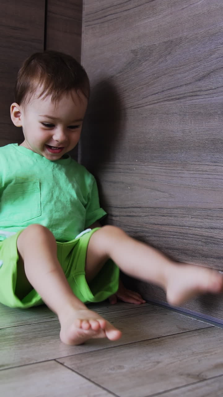 Lovely cute baby boy sitting on the floor. Little kid tries to say something with gestures. Vertical video
