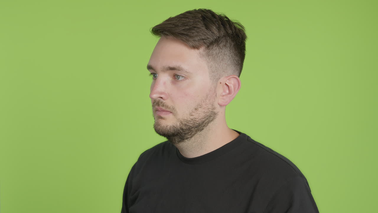 el hombre se quita la mascarilla protectora kn95 mientras mira a la izquierda de la cámara en la tecla cromática de pantalla verde