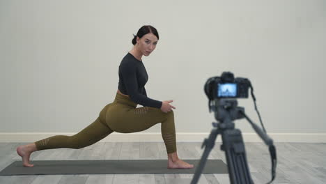 Yoga-En-Casa.-Mujer-Explicando-La-Postura-Del-Guerrero-(virabhadrasana),-Grabando-Un-Vídeo-Tutorial,-Mirando-A-La-Cámara.