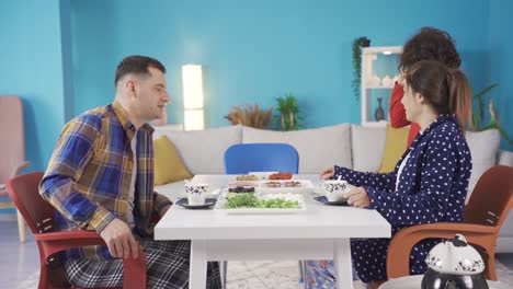 un niño de familia feliz despertando para el desayuno y sus padres sonriéndole.