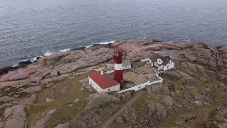 ryvingen island and lighthouse outside mandal in southern norway - old unmanned operative lighthouse for ship coastal navigation - aerial rotating around installation with ocean background