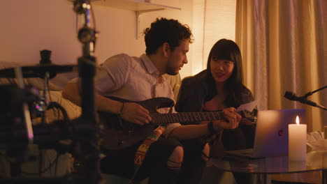 musicians collaborating on songwriting with guitar and laptop