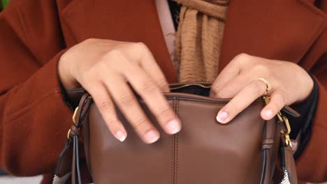 mujer abriendo una bolsa de cuero marrón