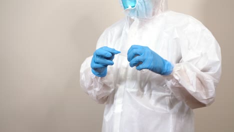 female doctor in ppe suit putting on gloves and sealing the suit with adhesive