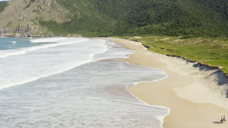 Aerial-view-near-the-sand-of-a-couple-walking-on-the-beach,-Lagoinha-Do-Leste-beach,-Florianopolis,-Santa-Catarina,-Brazil