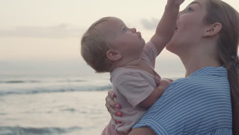 mother kissing toddler by ocean coast