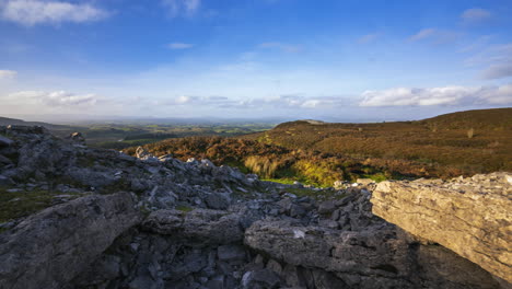 timelapse de movimiento panorámico del paisaje de naturaleza rural con ruinas de bloques de piedra de tumba de paso prehistórico en primer plano durante el día nublado soleado visto desde carrowkeel en el condado de sligo en irlanda