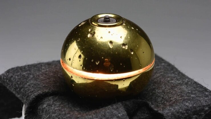 Emitting orange seam, polished gold sphere rotating on black felt pad at studio table, top cap