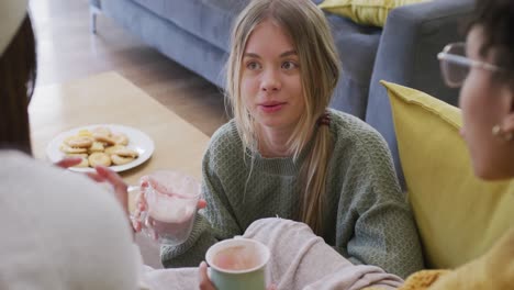 happy diverse teenager girls friends drinking coffee and talking at home, slow motion