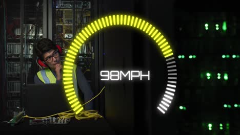Animation of speedometer over biracial man using laptop in server room