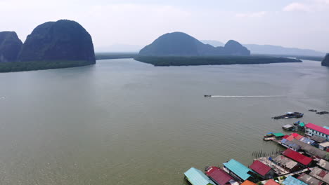 motorboat cruising along floating village in phang nga bay, thailand