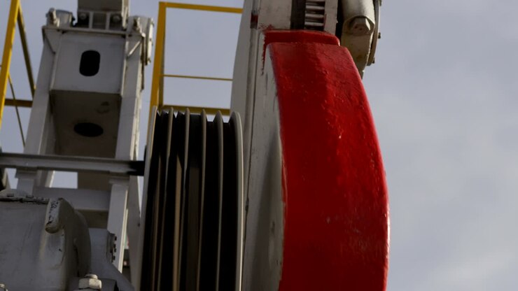 Primo piano di pompa di estrazione petrolifera circolare con cavi in gomma in funzione.